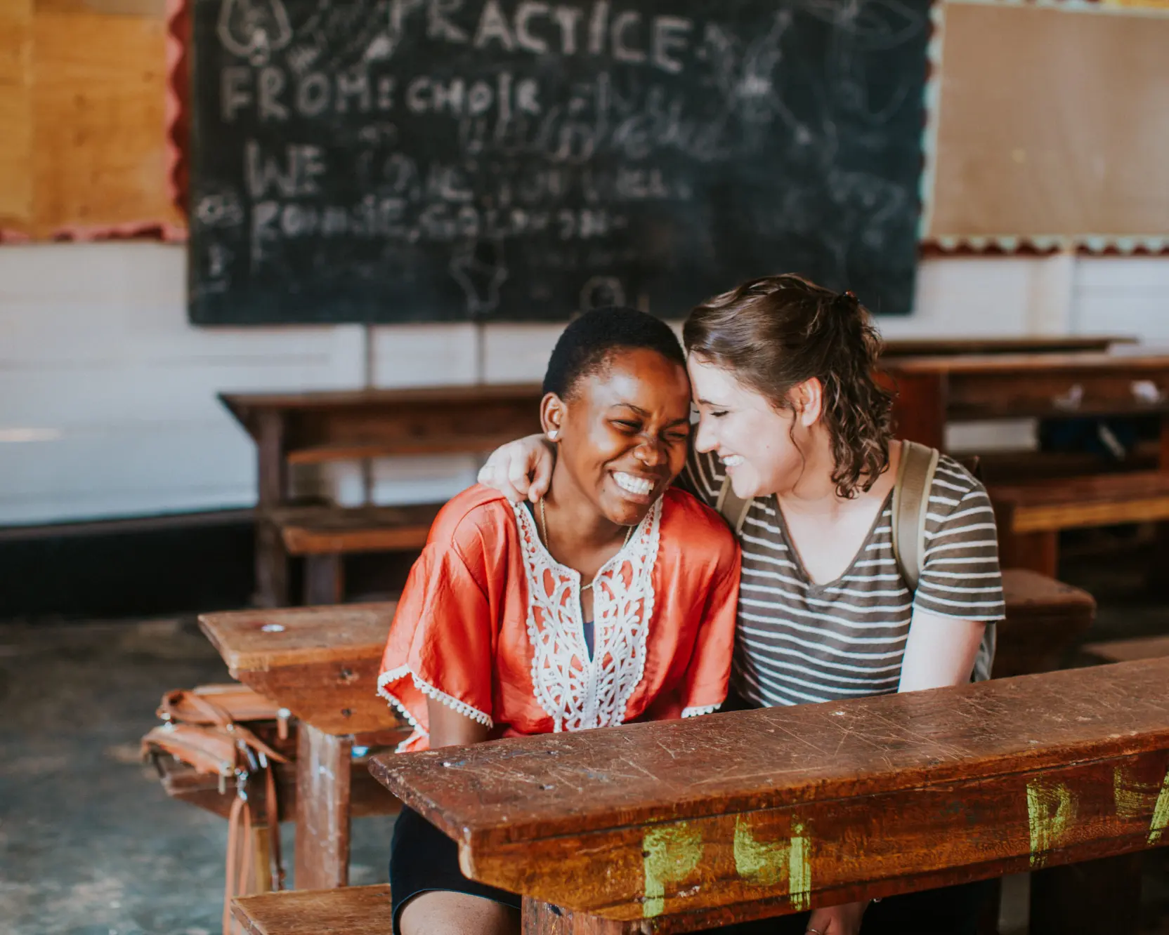 Two girls sitting at a desk in a classroom.